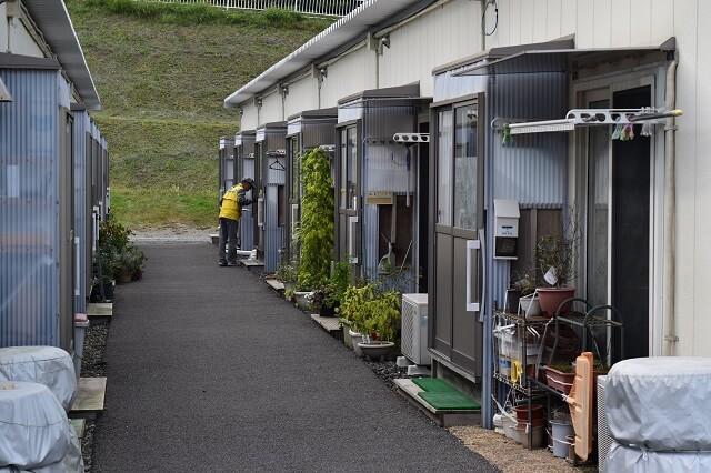 写真6：支援連絡員が仮設住宅の1軒1軒を回り声をかける様子を表す写真。