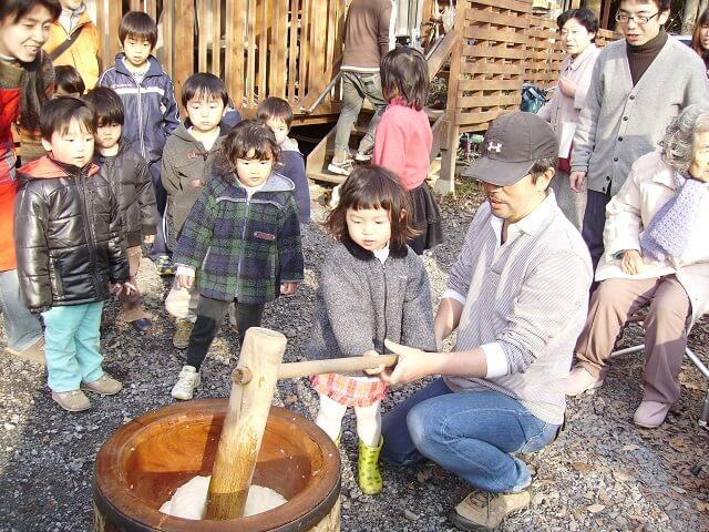 写真8：施設で行う正月恒例の餅つきの様子を表す写真。近隣の人や通りすがりの人も参加する。