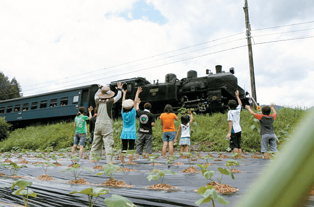 写真：大井川鐵道のSLに子供たちが手を振る様子を表す写真。